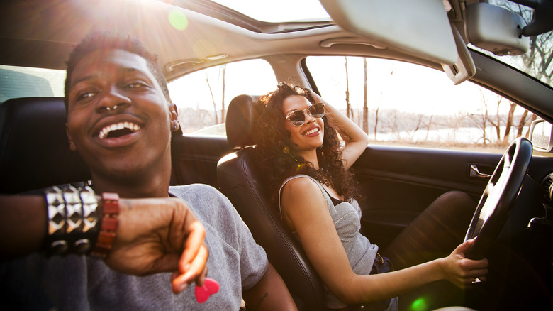Two people in a car together, with smiles on their faces and the sun shining
