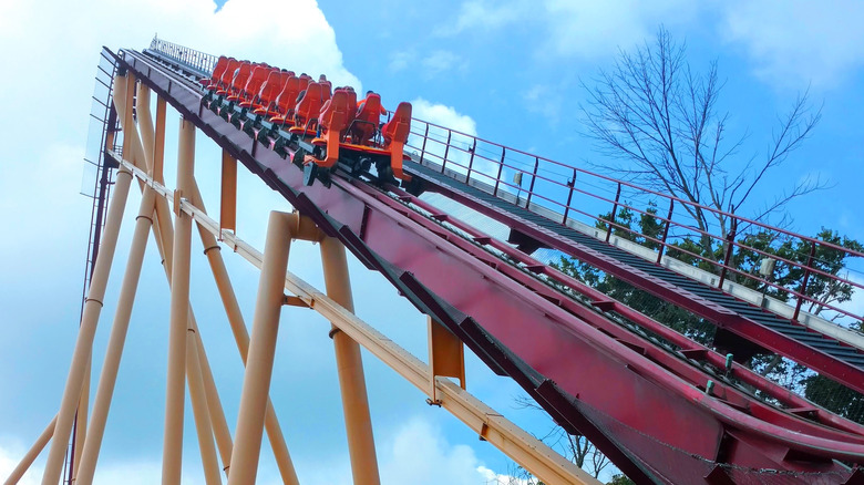 An empty roller coaster nearing the top of the first drop