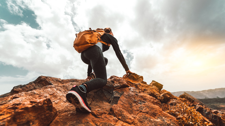 Person out climbing on top of a red rock high above the ground