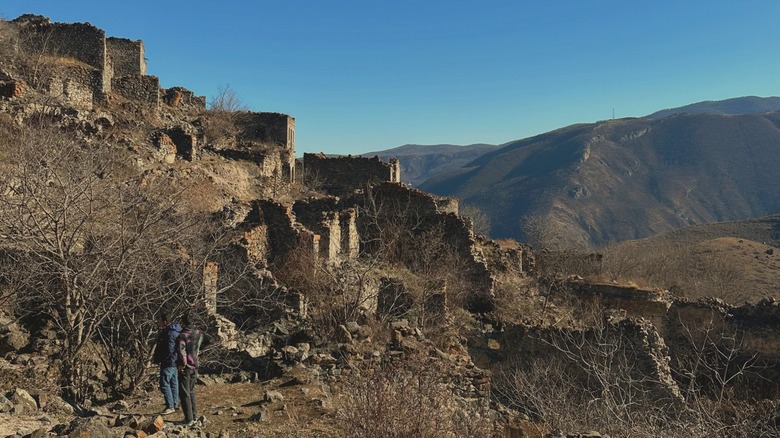 Two men walking amongst ruins of Hin Khot, an abandoned village in Syunik Province, Armenia