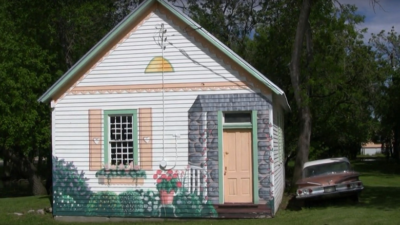 A mural of a stone entrance and flowering bushes on the front of a house