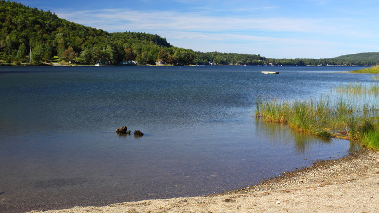 Blue skies over Swan Lake in Swanville, Maine has dark waters and sandy beaches.