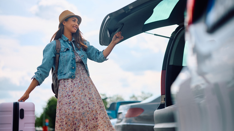 Woman with luggage and trunk open in parking lot