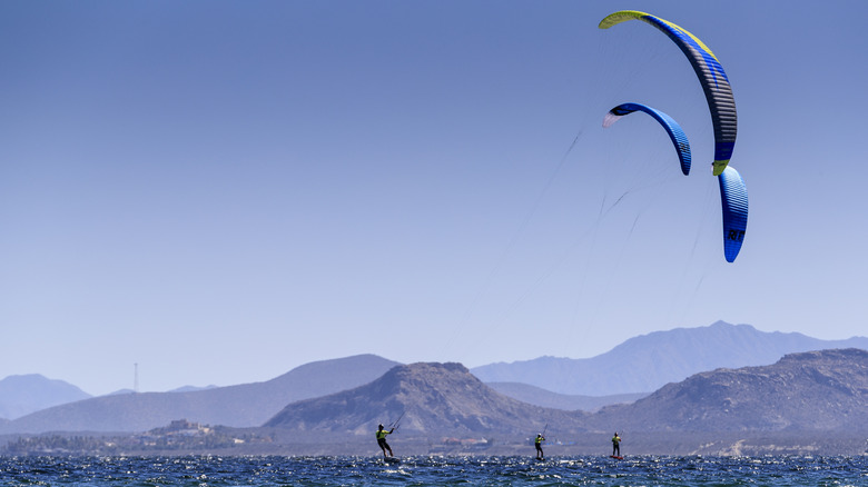 Windsurfers surfing against a mountain backdrop