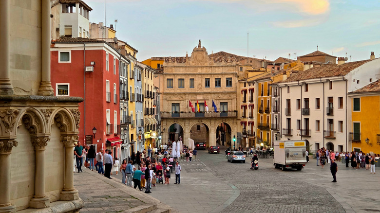 Colorful buildings around a cobblestone street filled with tourists in Cuenca, Spain