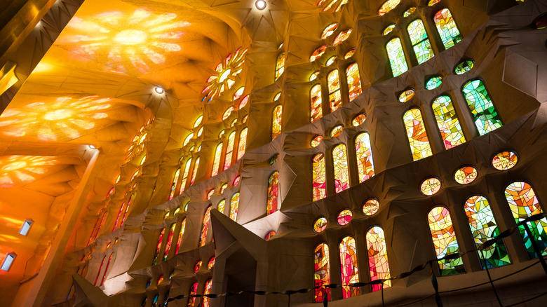 The stained glass windows of La Sagrada Família glow fiery orange and red in the afternoon light