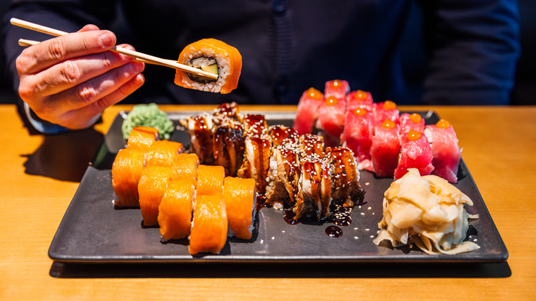 A person picking up sushi with chopsticks