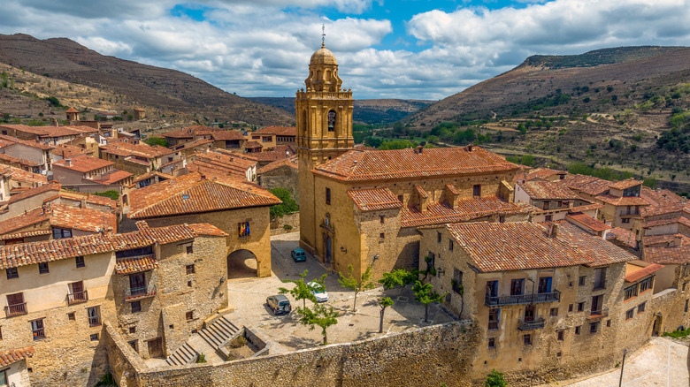 a church stands out in a golden skyline of Mirambel, a village surrounded by brown mountains