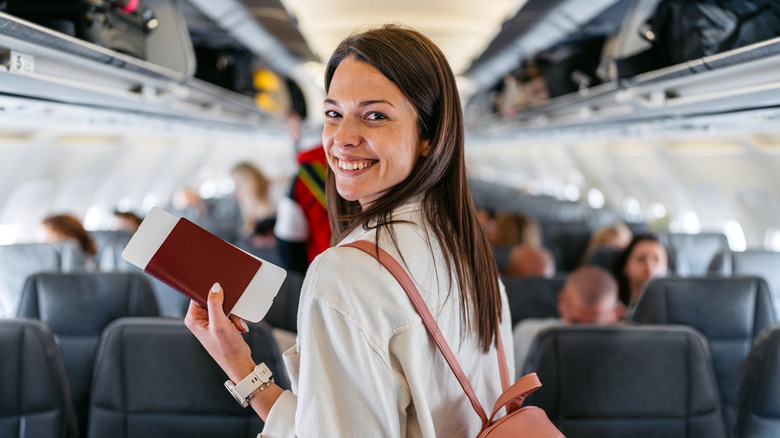 happy woman boards airplane with passport in hand