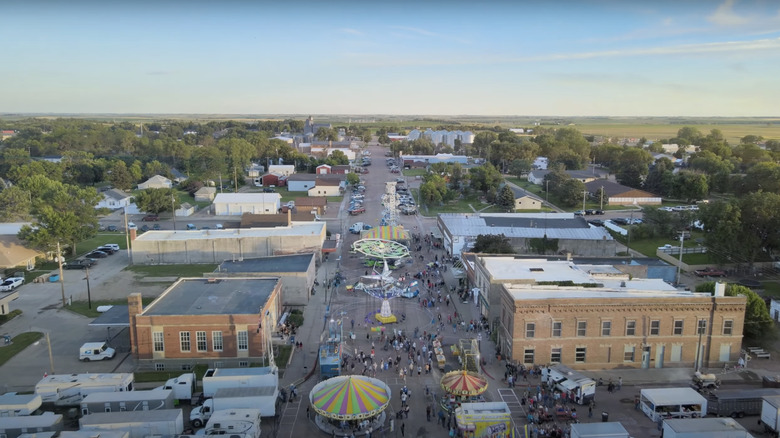 aerial view of a town with a carnival on a street and green trees