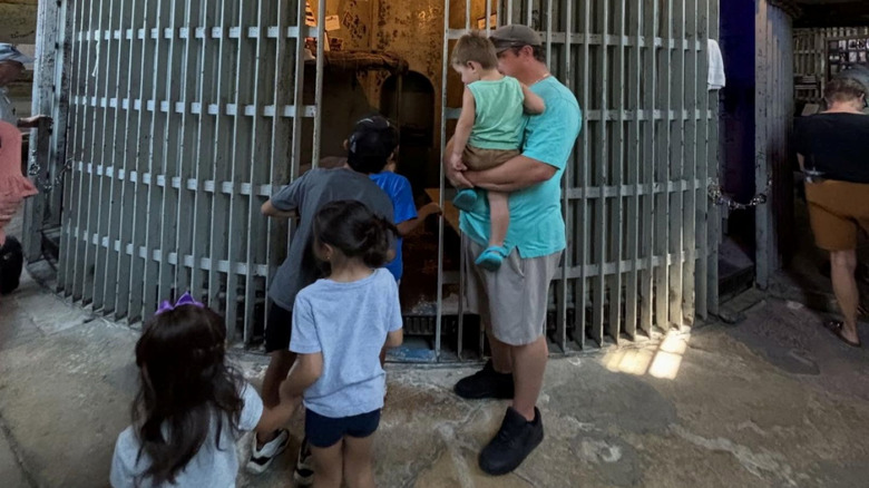 round jail cell with man holding baby in front of it