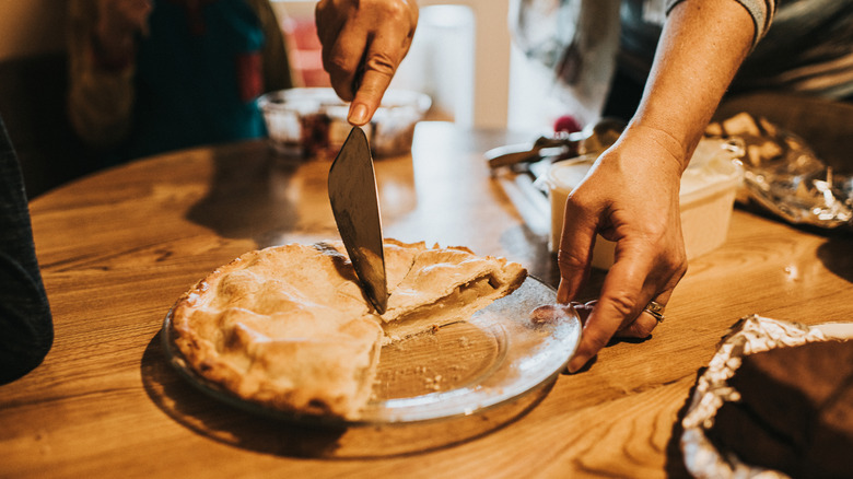 hand cutting into pie