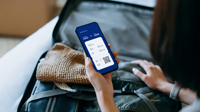 Woman holding her phone showing a plane ticket
