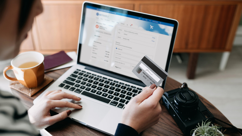 Person holding credit card with an open laptop in the background