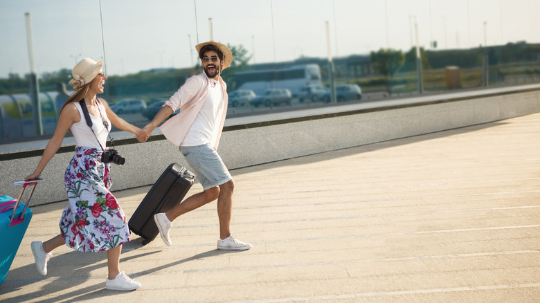 Smiling couple running with suitcases