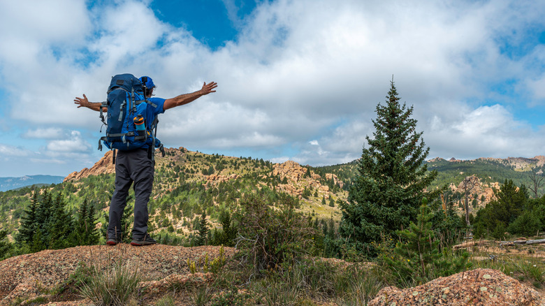 A backpacker stands in a mountainous landscape