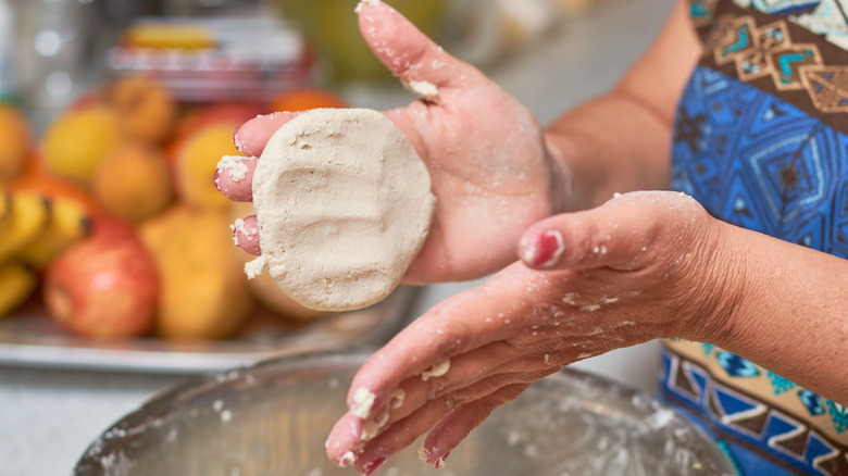 Person making tortillas by hand over a bowl