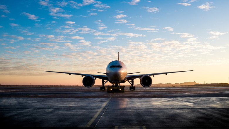 An airport on the runway with a sunset-lit sky in the background