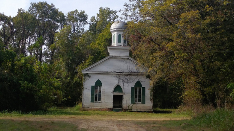 The abandoned Rodney Baptist Church, surrounded by trees and moss