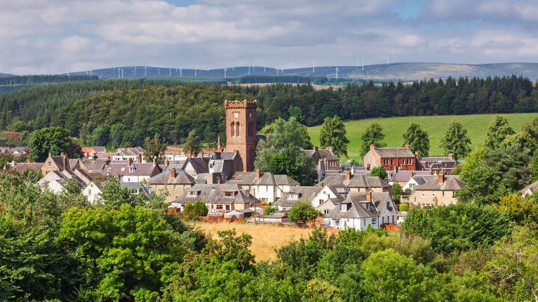Distant view of charming Doune houses and a clock tower surrounded by rolling hills and windmills