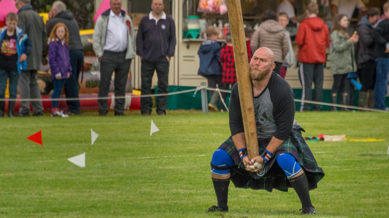 A highland games contestant lifts a caber.