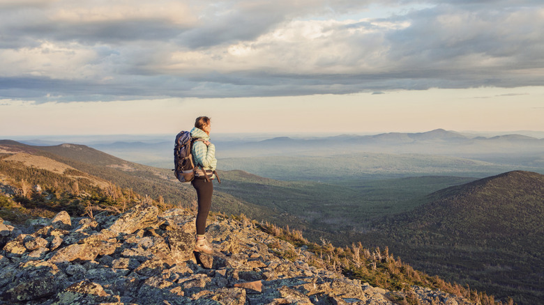 Woman admires the view from the top of a mountain on the Appalachian trail in Maine