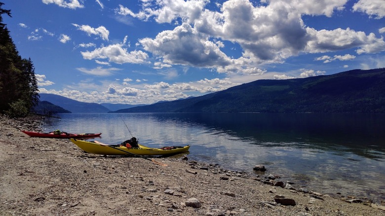 Lake shore of Adams Lake with yellow kayaks on pebbled beach