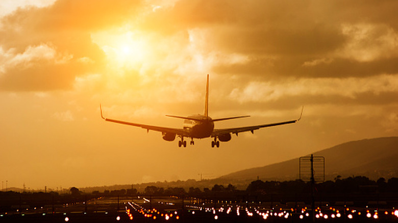 Airplane landing on runway in Cape Town, South Africa, at sunset