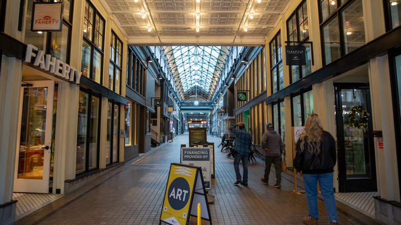 People walking down a skylight-covered walkway lined with shops