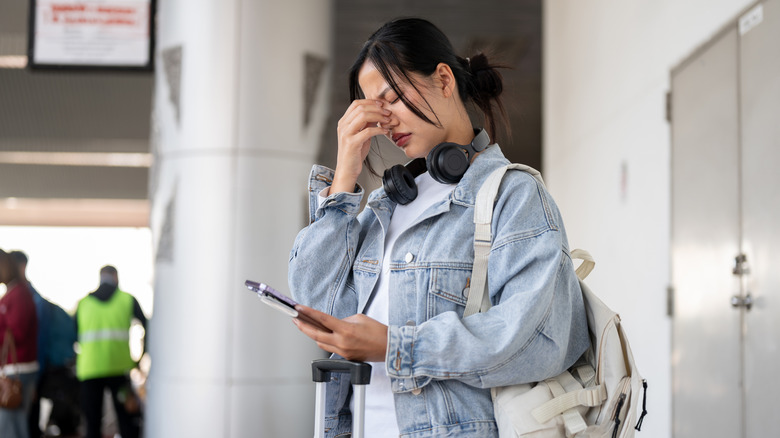 Stressed woman looking at her phone in the airport
