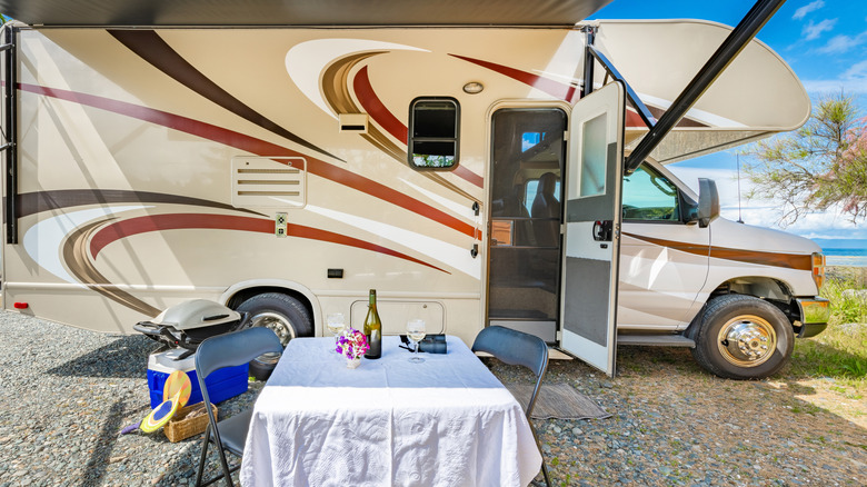 Image of RV motorhome with a table and folding chairs outside