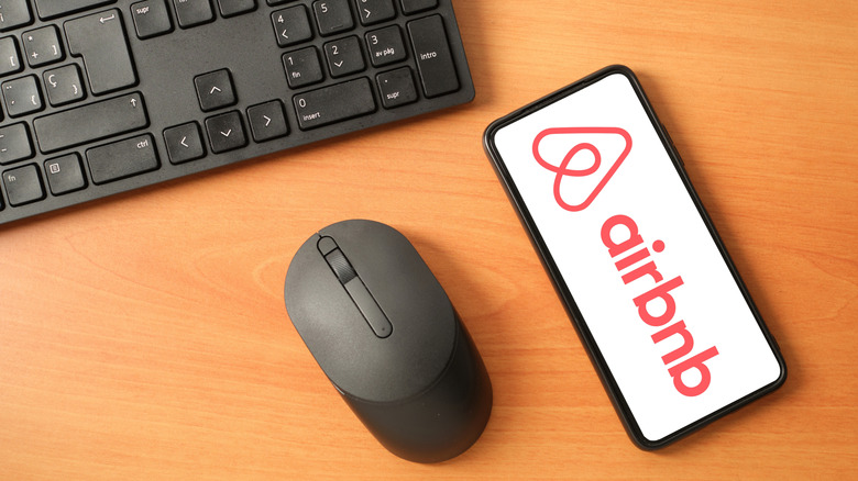 iPhone screen showing the Airbnb logo and a computer keyboard