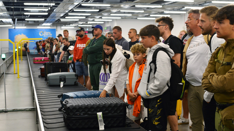 Tourists crowding baggage carousel