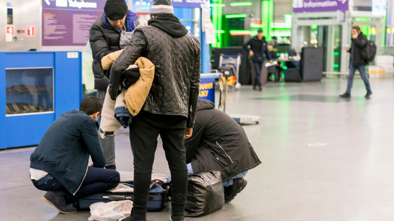 Man rummaging for items in bag at airport