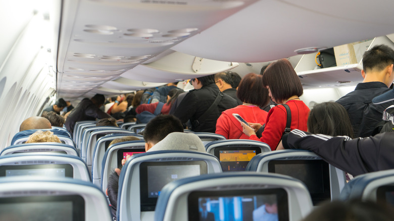 People standing in aisle on airplane upon landing