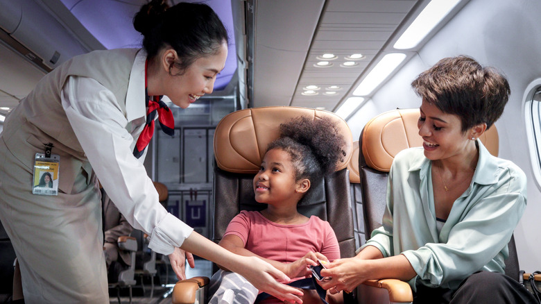 Flight attendant helping passengers on a plane