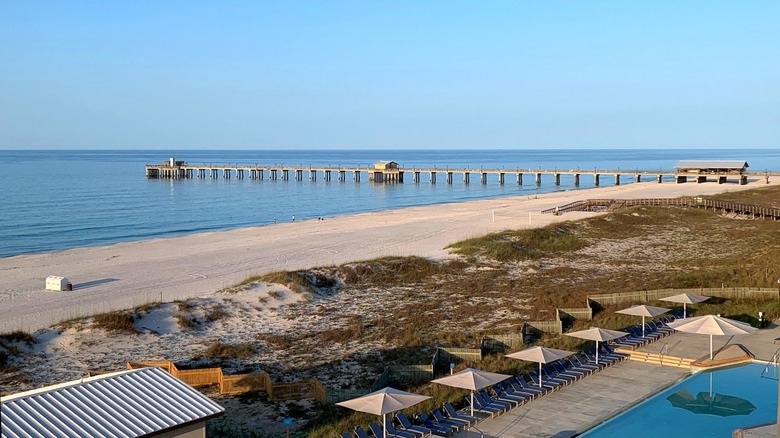 The beach at Gulf Shores State Park with a pier stretching over the water and a pool