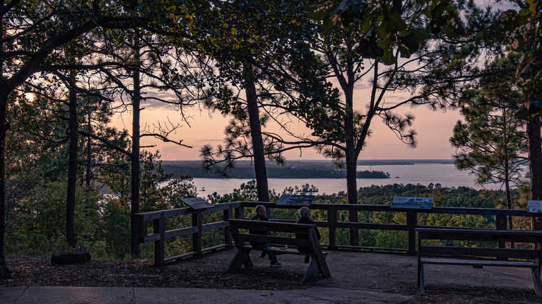 Two people sitting on a bench at Overlook Park in Dadeville, Alabama watching the sunset over Lake Martin
