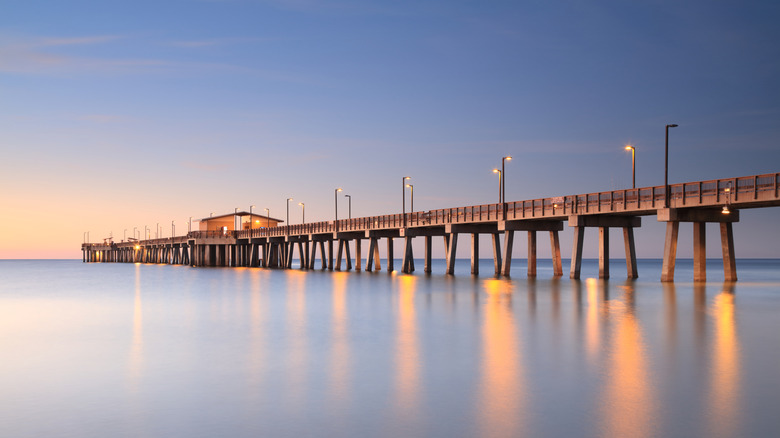 Fishing pier at sunset with lights illuminating water below