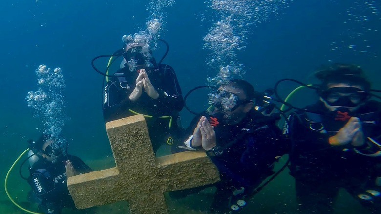 Scuba divers pray underwater around a sunken tombstone at Blue Water Park in Alabama.