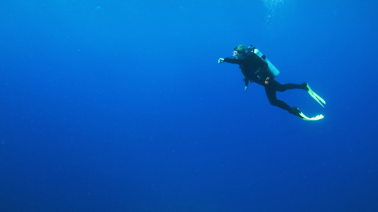 A scuba diver swimming through empty blue water.