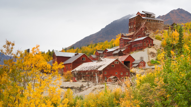Red abandoned buildings surrounded by yellow autumnal trees in Kennecott, Alaska