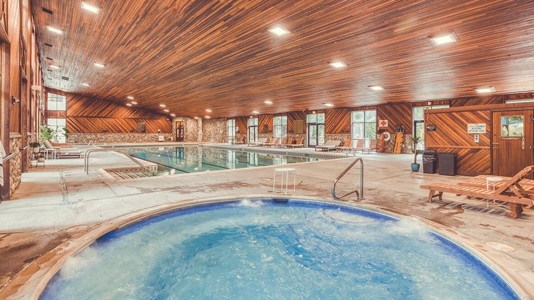 A hot tub in the foreground and a pool behind it beneath wooden-slatted ceilings at Bonneville Hot Springs Resort & Spa