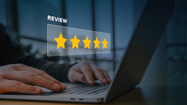 a person's hands using a laptop with a 5-star review icon positioned above their hands