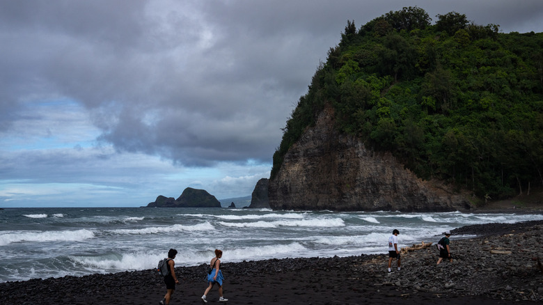 Hikers on black sand beach in Hawaii