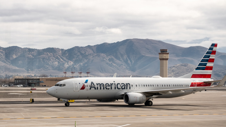 An American Airlines plane sitting on a tarmac at an airport with mountains in the background