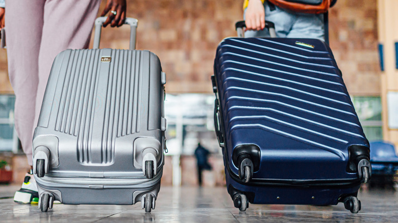 Two people dragging bags behind them in an airport