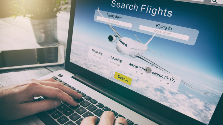 A traveler books a flight on a laptop through an unnamed travel search engine