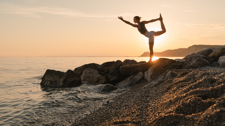 A woman practicing yoga at sunset.