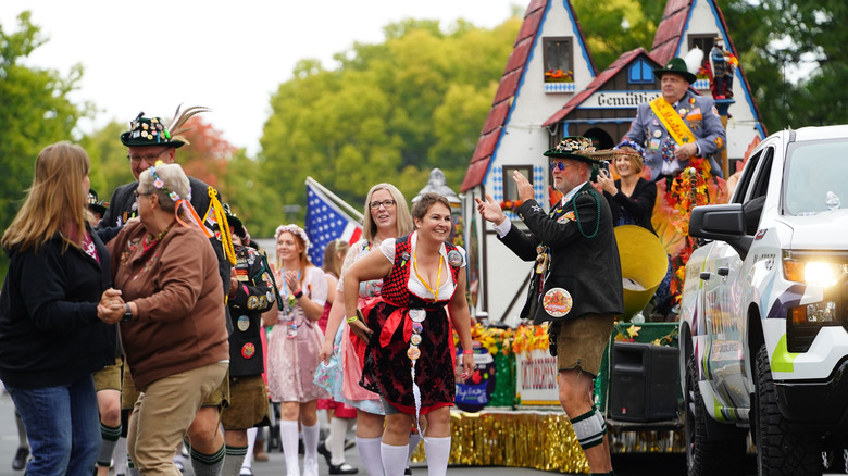 women and men in traditional Bavarian attire dancing at a colorful Oktoberfest